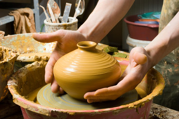 hands of a potter, creating an earthen jar on the circle