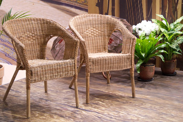 Two straw armchairs in a hall with flowers