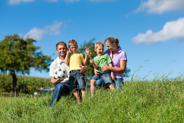 Fototapeta premium Familie mit Kindern und Fußball auf einer Wiese