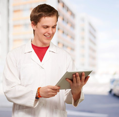 portrait of young academic holding a digital tablet against a bu