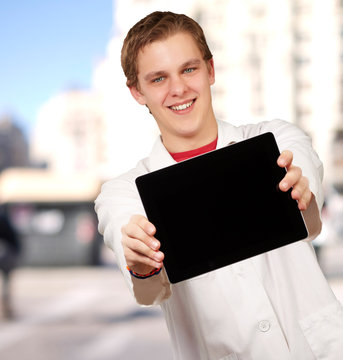 portrait of young man showing digital tablet against a building