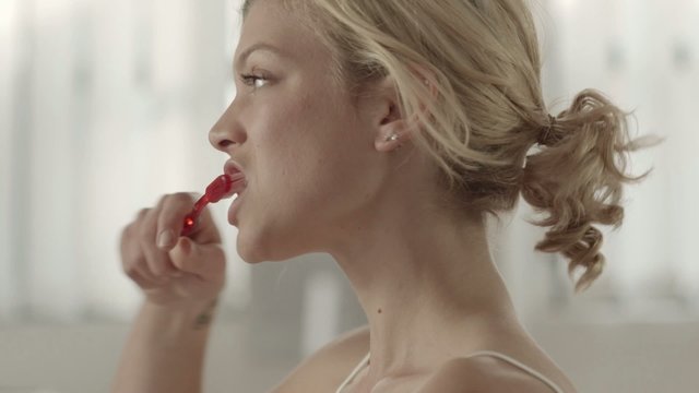 Happy Blonde Young Woman Brushing Teeth And Smiling At Camera