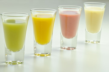 four colourful fruit smoothies in glasses