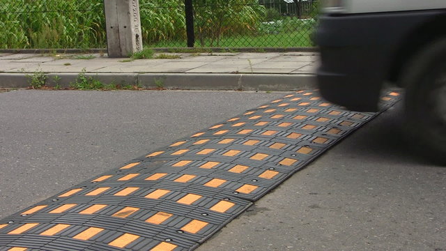 Car driving over street bump at speed limit zone