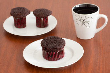 chocolate muffins on a plates and cup with tea on table