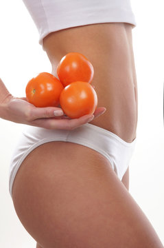 Sexy body of a young woman holding fresh tomatoes