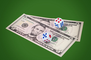 Money with dice on green background.