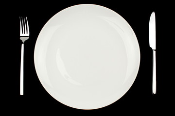Knife, fork and plate on a black background.