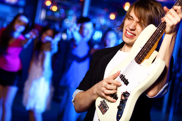 Young guitar player performing in night club © Sergey Nivens