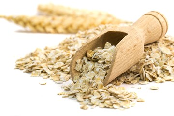 Oatmeal flakes with wooden scoop on white background