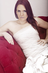 Naklejka premium young red haired beautiful bride on red sofa