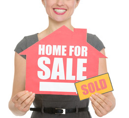 Closeup on home for sale sold sign holding by happy female