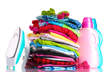 Pile of colorful clothes and electric iron with detergent