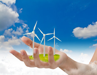 Wind turbines on hand over blue sky