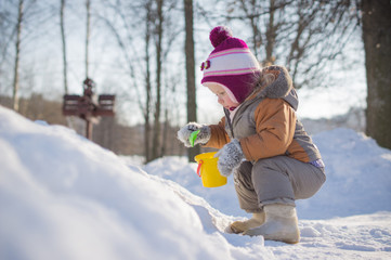 Fototapeta na wymiar Adorable baby dig snow with small shovel on playground