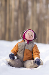 Fototapeta na wymiar Adorable baby sit on snow road in park