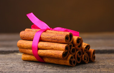 Cinnamon sticks on wooden table on brown background