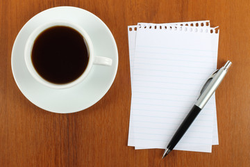 Cup of coffee, paper and pen on wooden background