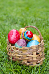 Easter eggs in basket on green grass