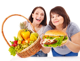 Women choosing between fruit and hamburger.