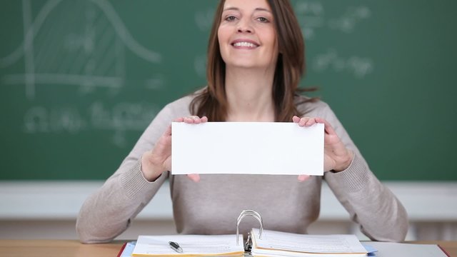 freundliche lehrerin zeigt wei&szlig;es schild