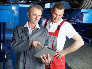 Master mechanics inspecting the engine of a car with touchpad