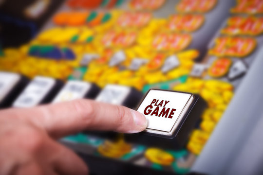 Man's hand pressing play button on a slot machine