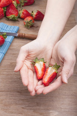 studio-shot of woman`s hands showing a halved fresh strawberry