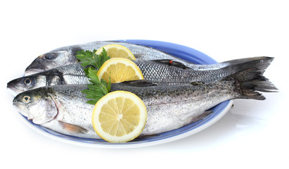 Fresh fishes with lemon and parsley on plate isolated on white