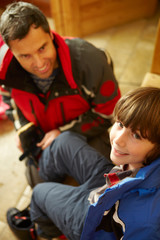 Father Helping Son To Put On Warm Outdoor Clothes And Boots