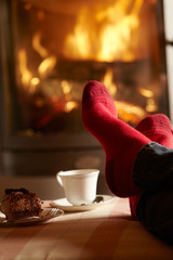 Close Up Of Mans Feet Relaxing By Cosy Log Fire With Tea And Cak