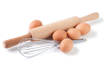 Brown eggs, rolling pin and wire whisk isolated over white