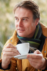 Man In Outdoor CafŽ With Hot Drink  Wearing Winter Clothes