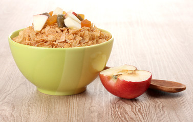 tasty cornflakes in bowl with dried fruits and apple