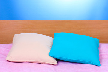Fototapeta na wymiar bright pillows on bed on blue background