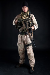 Fototapeta premium Soldier with rifle against black background.