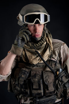 Soldier talking at the radio against black background.