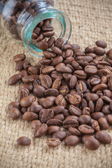 Coffee beans spilled out from glass little jar