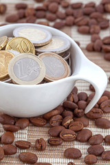 Coffee cup full of Euro coins, spilled coffee beans