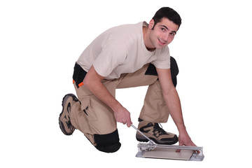 Man kneeling to cut tile to size