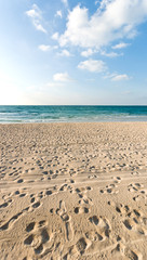 sandy beach with lots of footprints and a blue sky with clouds