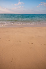 Fototapeta na wymiar piaszczysta plaża z dużą ilością śladów i błękitne niebo z chmurami