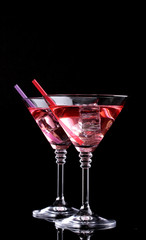 Red cocktail in martini glasses isolated on black