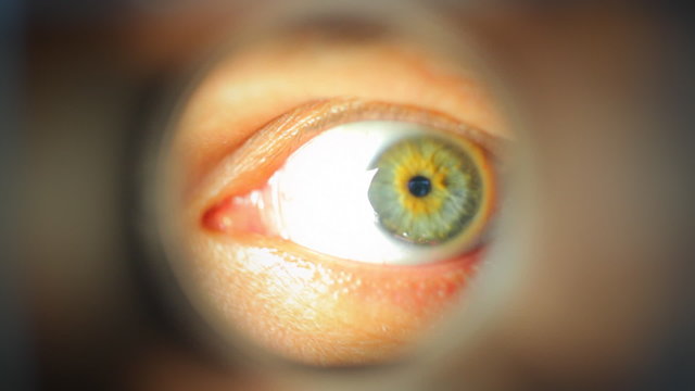 Mans eye looking through a blured hole