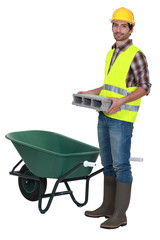 Man placing brick into wheelbarrow