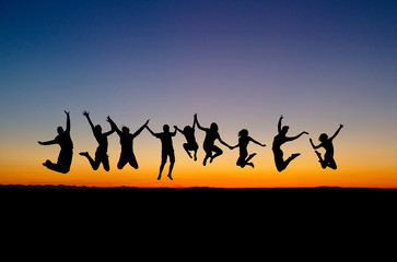 silhouette of friends jumping in sunset