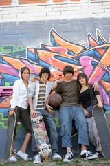 teenagers posing in front of tagged wall