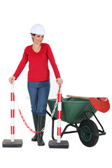 Woman worker with a wheelbarrow and barrier