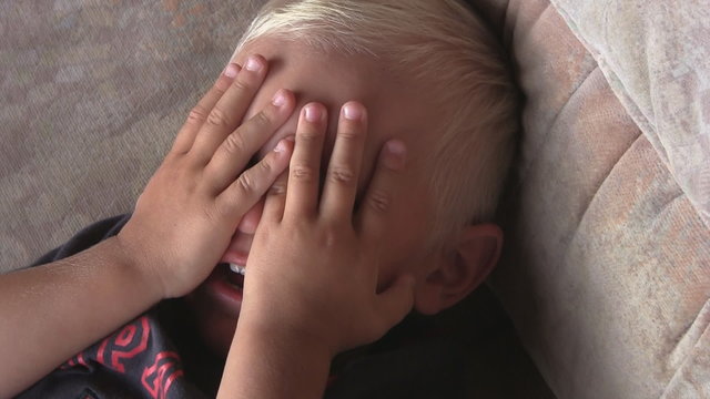 2 year old boy cavers face with hands, close-up
