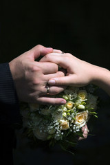 Hands with rings on wedding bouquet